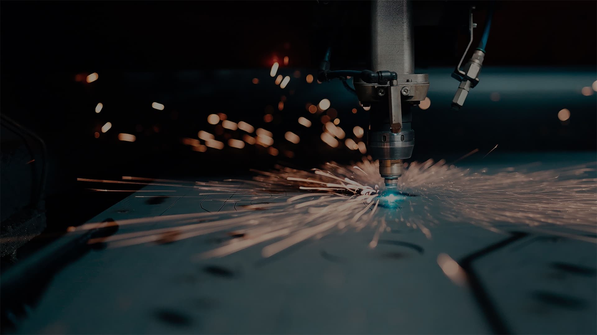 Tête de découpe laser en action sur une tôle d’acier, gerbe d’étincelles
